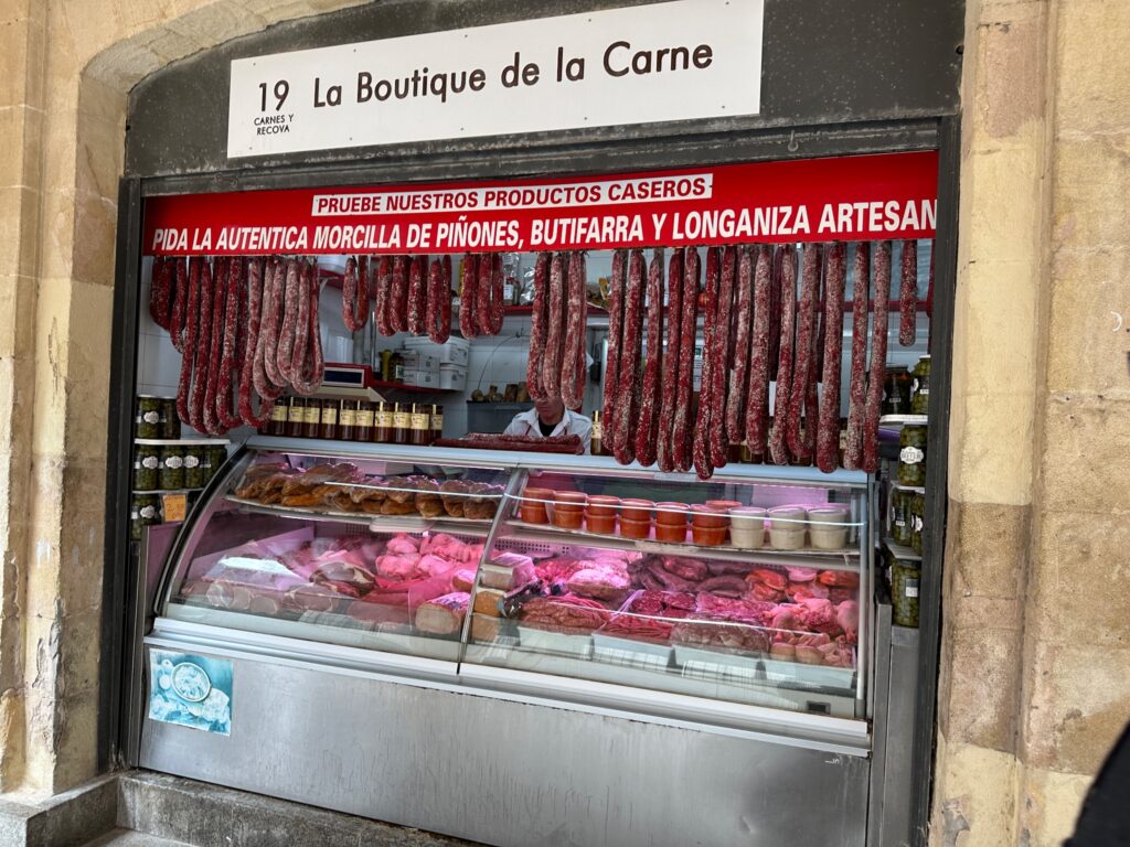 Spanish butcher shop "La Boutique de la Carne" displays hanging cured meats and fresh cuts in refrigerated cases
