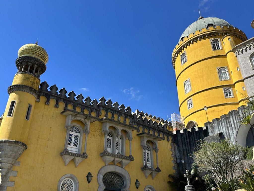 Bright yellow palace with ornate towers and crenellated walls against clear blue sky