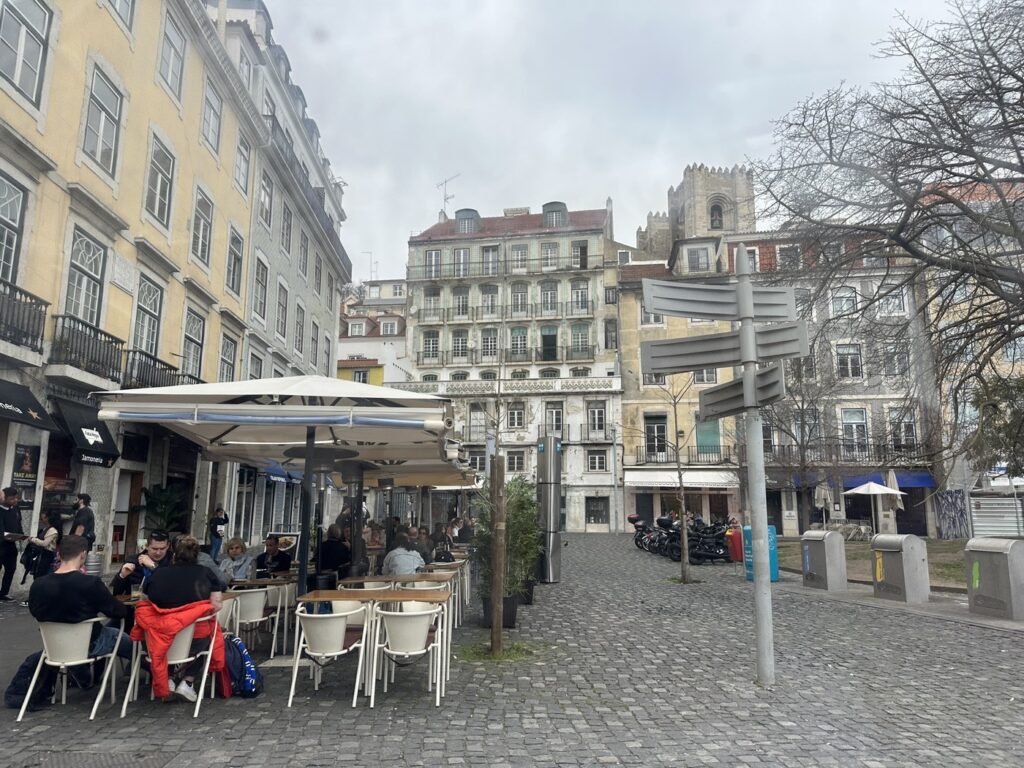 Outdoor café with white umbrellas in a European town square surrounded by historic buildings and a church tower