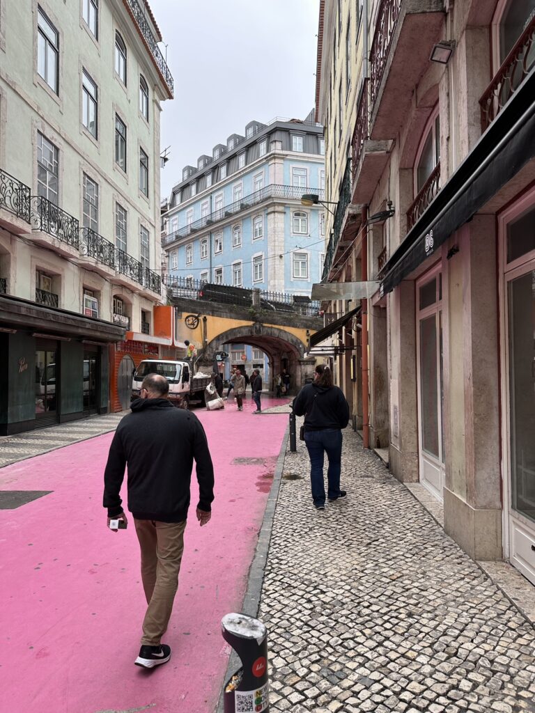 Man jogging through a European street with pink pavement, historic buildings, and cobblestone sidewalks