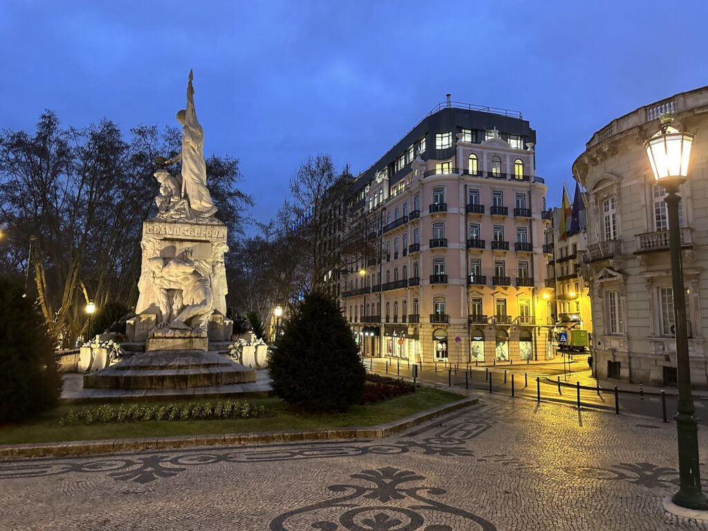 Illuminated monument and elegant Haussmann buildings in a European plaza at twilight with decorative paving