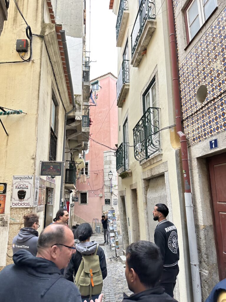 Tourists walking through a narrow cobblestone alley in a historic European city with colorful buildings and traditional architecture