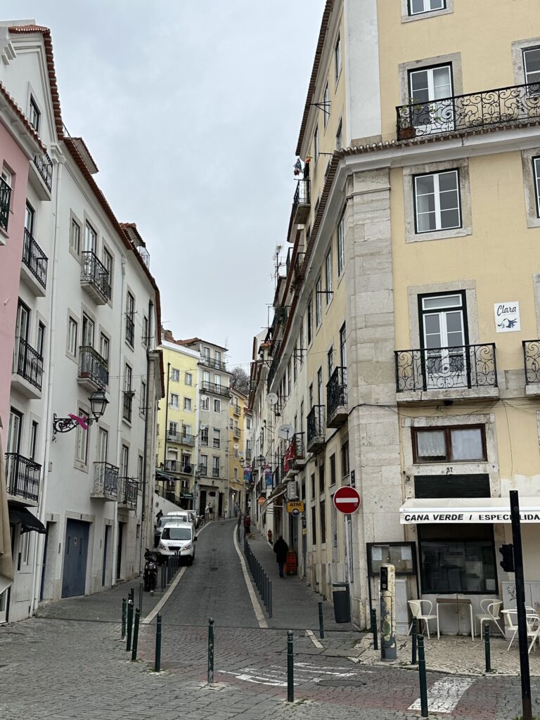 Narrow cobblestone street lined with colorful historic buildings and wrought iron balconies in a European city neighborhood
