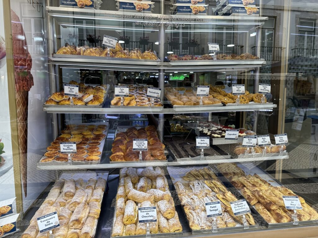 Display case filled with various fresh baked goods including croissants, pastries, and bread in a bakery shop window