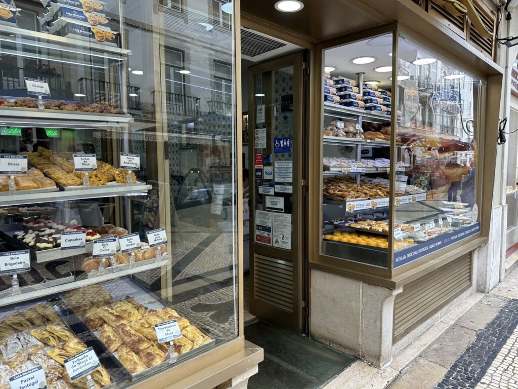 Bakery storefront with glass windows displaying pastries, breads, and baked goods on multiple shelves